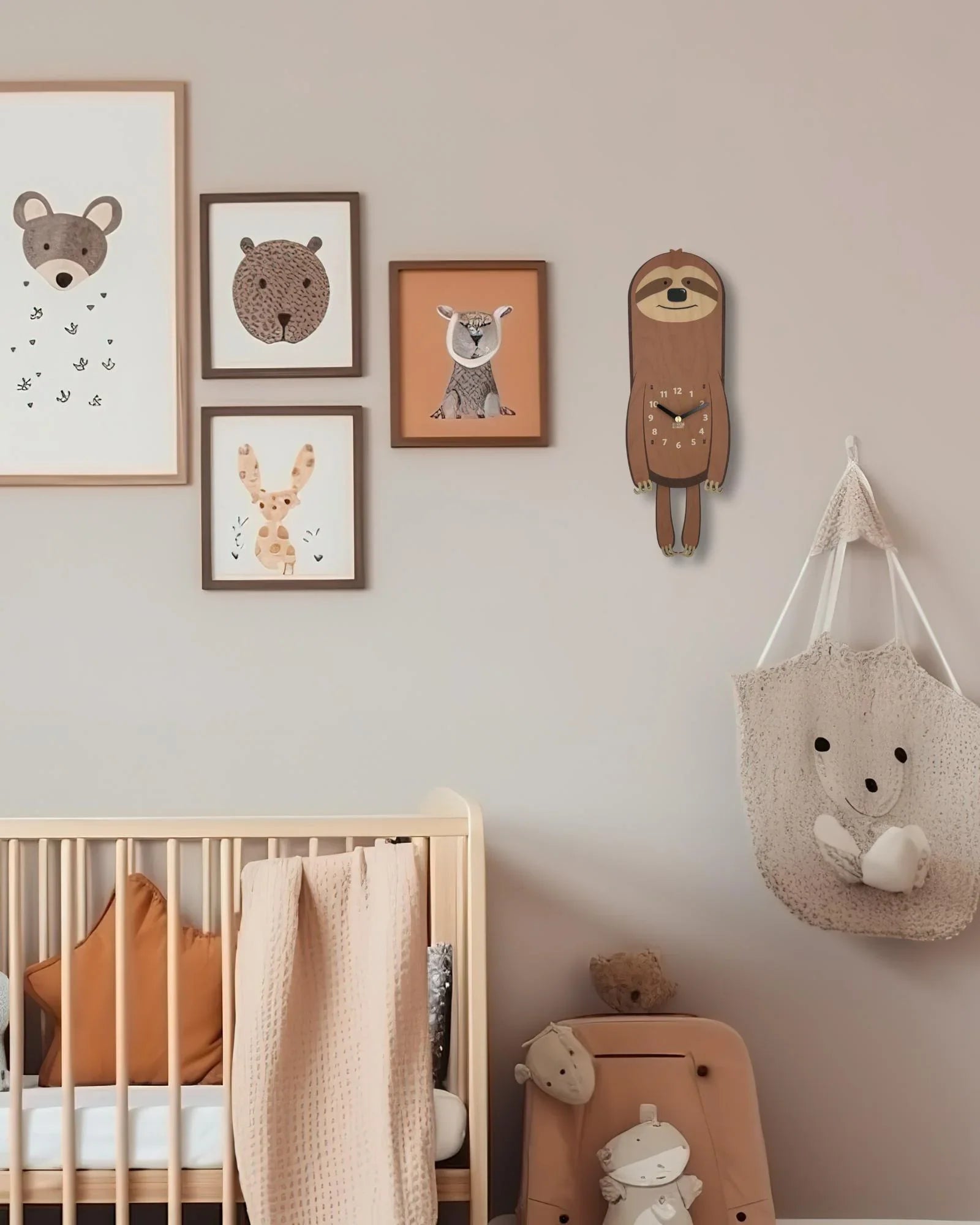 Sloth wall clock and animal art above nursery crib in cozy, neutral-toned children's room.