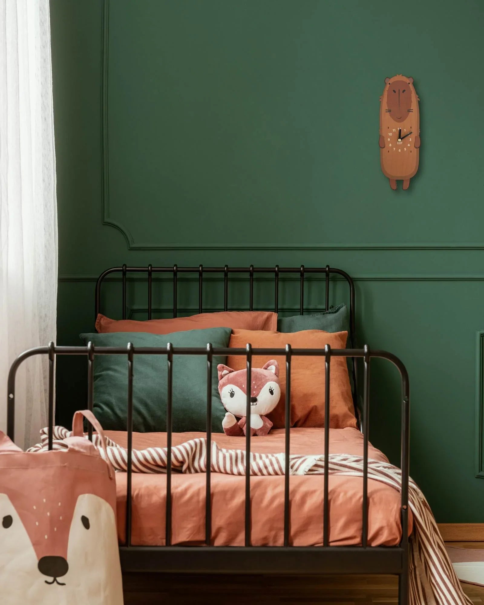 Whimsical animal-shaped wall clock in a cozy kids bedroom with forest-themed decor and plush toys
