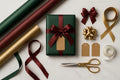 Elegant gift wrapping set with green paper, gold and burgundy ribbons, tags, and scissors.